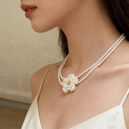 Hand beaded floral necklace made with pearl style beads, featuring a delicate flower centerpiece and double strand design