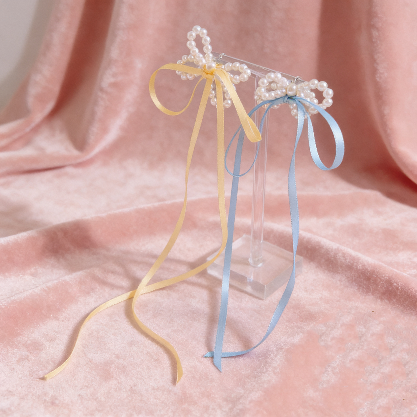 Cute pearl bow stud earrings laid flat on neutral background