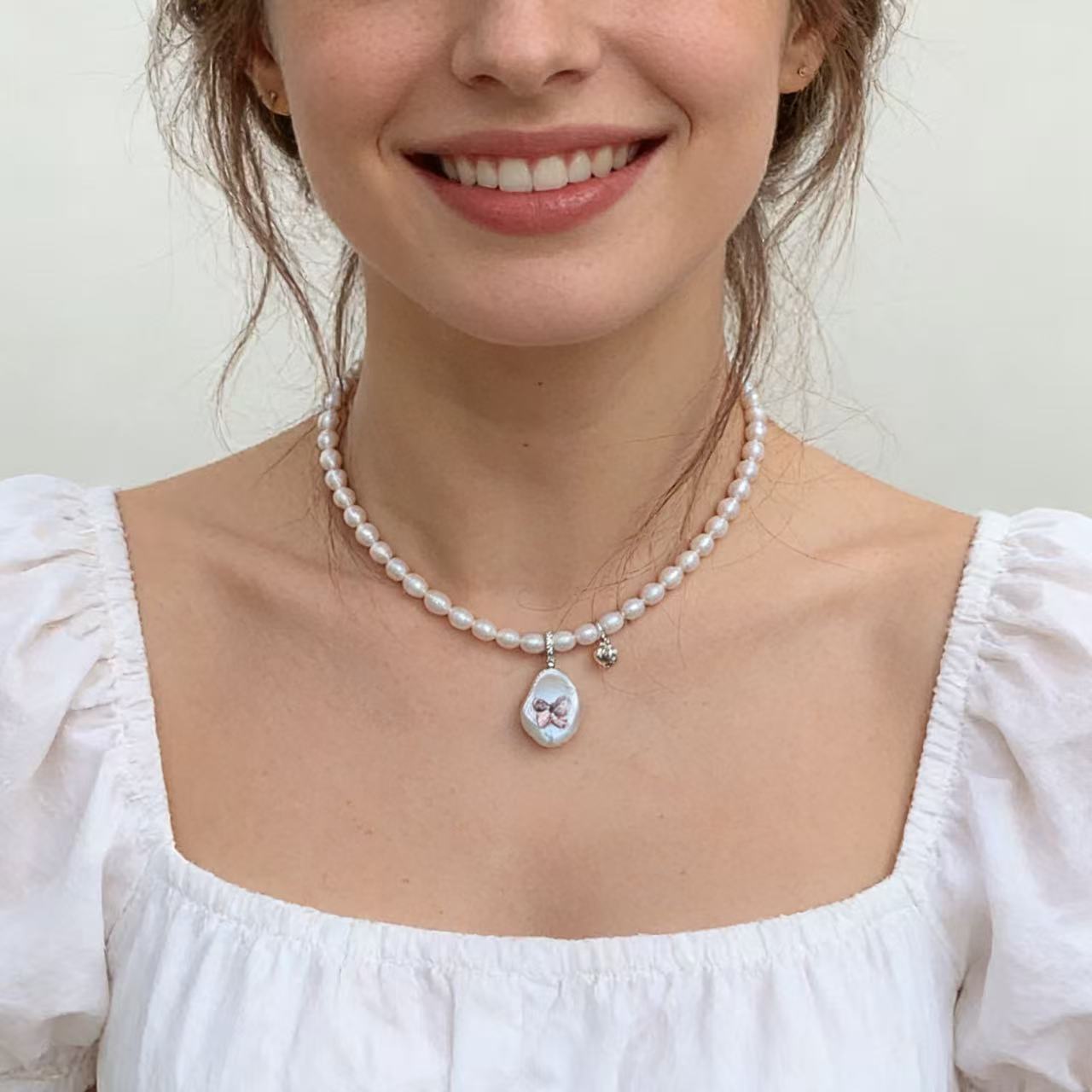 Close-up of baroque pearl pendant with Swarovski crystal butterfly charm