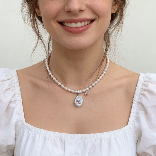 Close-up of baroque pearl pendant with Swarovski crystal butterfly charm