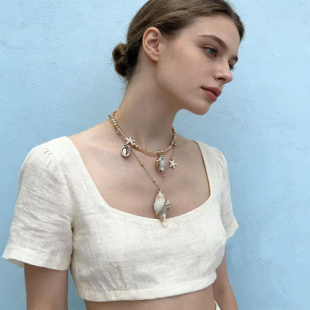 Layered shell pearl charm necklace worn on neck