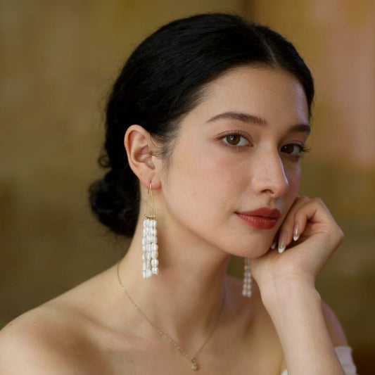 Multi strand pearl fringe drop earrings on pink background