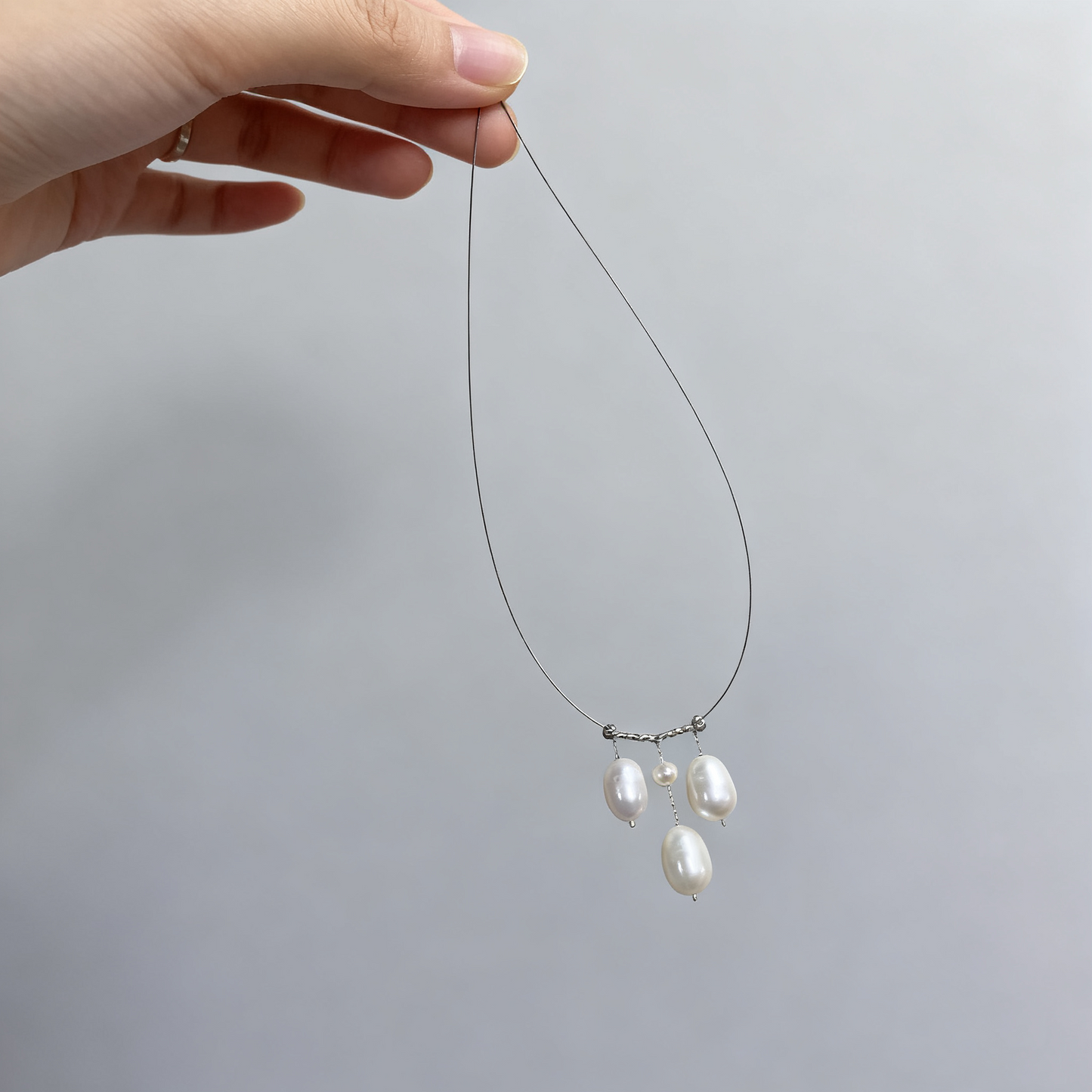 Pearl drop necklace with triple pendant design on silver tone chain