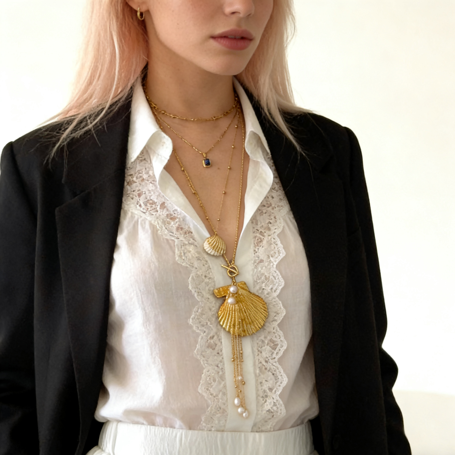 Model wearing a handmade gold shell and pearl pendant necklace in a layered styling