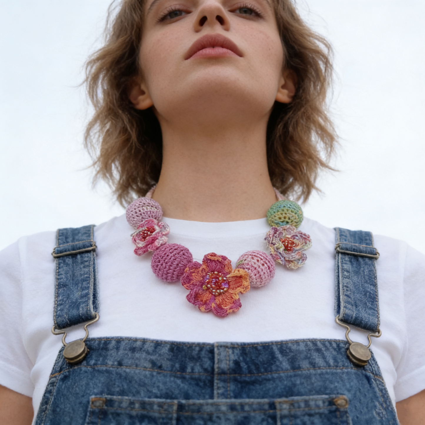 Hand crochet floral statement necklace worn on model with soft pastel crochet flowers