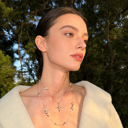 Layered pearl beaded cross necklace worn on model
